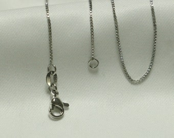 May include: A silver chain necklace with a lobster clasp and a jump ring. The chain is made of small, linked squares.