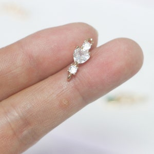 May include: Gold charm with a heart-shaped rhinestone and two smaller round rhinestones.