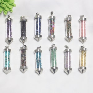May include: Twelve silver pendants with clear glass tubes filled with various colored crystals. Each pendant has a pointed tip and a silver loop at the top for attaching a chain.
