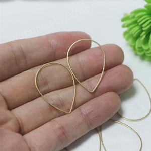 Pode incluir: Um conjunto de bases de brincos de fio em forma de lágrima douradas. As bases são de metal e estão prontas para serem usadas na fabricação de joias.