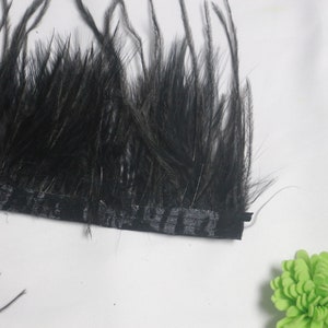 Pode incluir: Bordado de penas pretas com um suporte de tecido estampado em preto e branco.