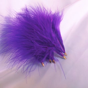 May include: A bunch of purple ostrich feathers with gold wire stems.