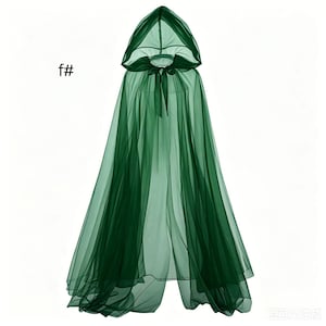 Puede incluir: Una capa con capucha de color verde oscuro transparente hecha de tela de tul ligera. La prenda presenta una capucha puntiaguda y un cierre de lazo a juego en el cuello. El texto f# es visible en la parte superior izquierda de la imagen.