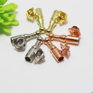 K&ouml;nnte beinhalten: Sortiment von sechs Metall-Stiftverschl&uuml;ssen in verschiedenen Ausf&uuml;hrungen, darunter Gold, Silber und Ros&eacute;gold. Jeder Stiftverschluss hat eine zylindrische Form mit abgerundeter Oberseite und einem Stift an der Unterseite.