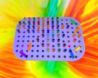 May include: A purple tray with a grid of holes, filled with colorful, translucent tubes. The tubes are arranged in a semi-circle pattern, with the colors ranging from red to blue to green.