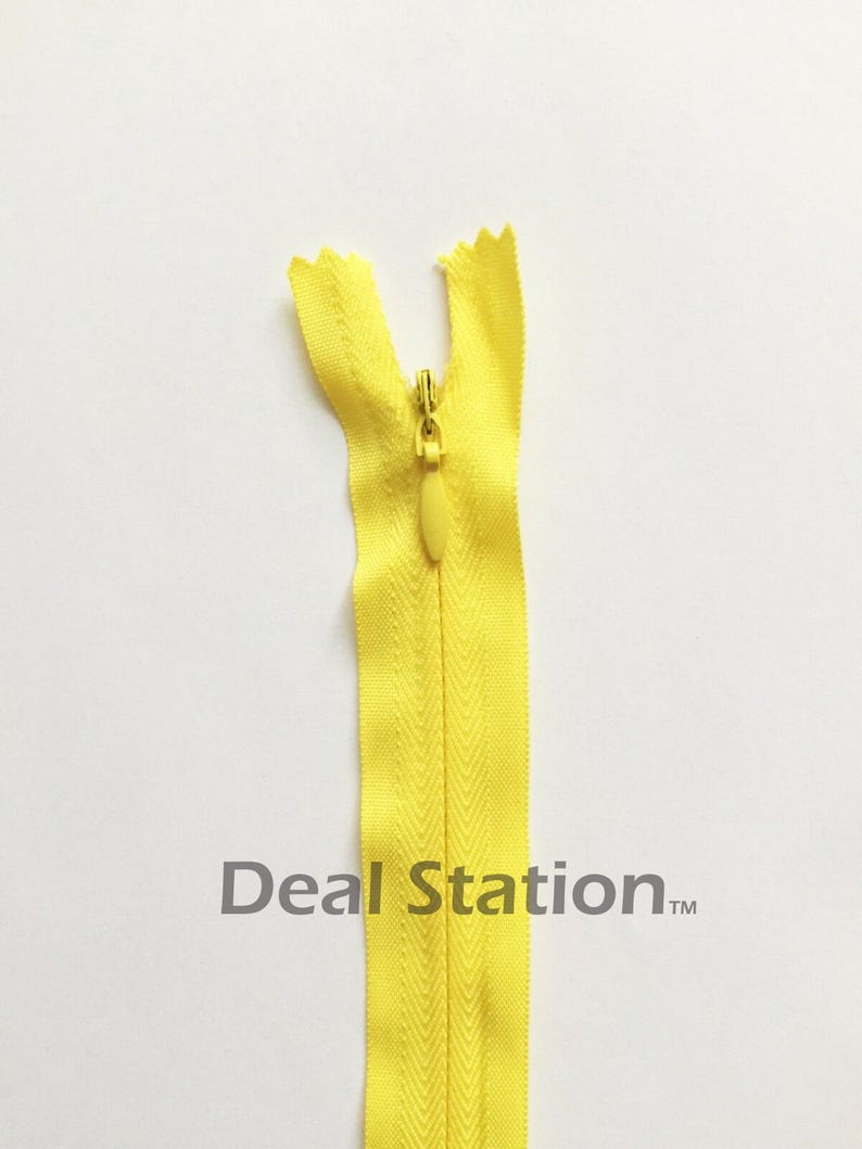K&ouml;nnte beinhalten: Ein leuchtend gelber Rei&szlig;verschluss mit passendem Zipper vor wei&szlig;em Hintergrund. Der Rei&szlig;verschluss ist ge&ouml;ffnet und zeigt die Z&auml;hne und das Stoffband. Der Text "Deal Station" ist auf dem Rei&szlig;verschluss aufgedruckt.
