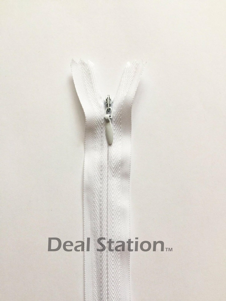 K&ouml;nnte beinhalten: Ein wei&szlig;er, unsichtbarer Rei&szlig;verschluss mit silbernem Metallschieber. Der Rei&szlig;verschluss ist ge&ouml;ffnet und zeigt die Z&auml;hne und das Stoffband. Der Text "Deal Station" ist unten im Bild aufgedruckt.