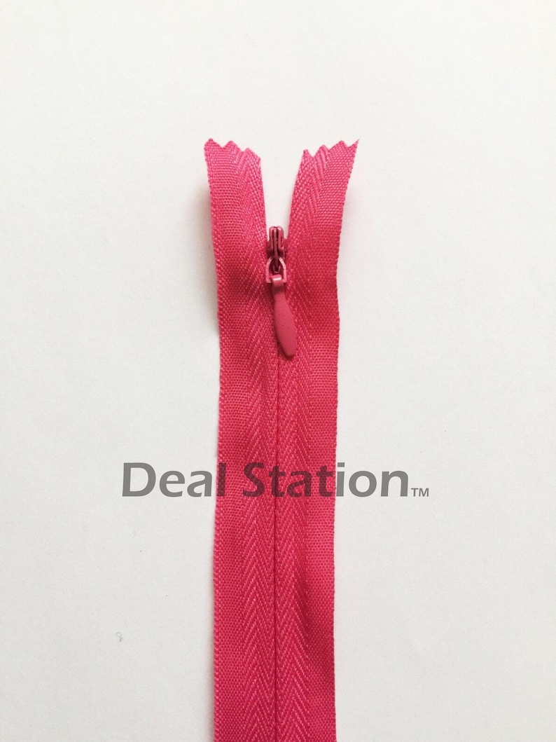 K&ouml;nnte beinhalten: Ein leuchtend pinkfarbener Rei&szlig;verschluss mit passendem Zipper vor wei&szlig;em Hintergrund. Die Z&auml;hne des Rei&szlig;verschlusses sind sichtbar, und das Stoffband hat ein dezentes Fischgr&auml;tmuster. Der Text "Deal Station" ist auf dem Band aufgedruckt.
