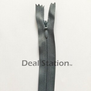 K&ouml;nnte beinhalten: Ein grauer, unsichtbarer Rei&szlig;verschluss mit passendem Zipper vor wei&szlig;em Hintergrund. Die Z&auml;hne des Rei&szlig;verschlusses sind im geschlossenen Zustand verdeckt. Der Text "Deal Station" ist im Hintergrund aufgedruckt.