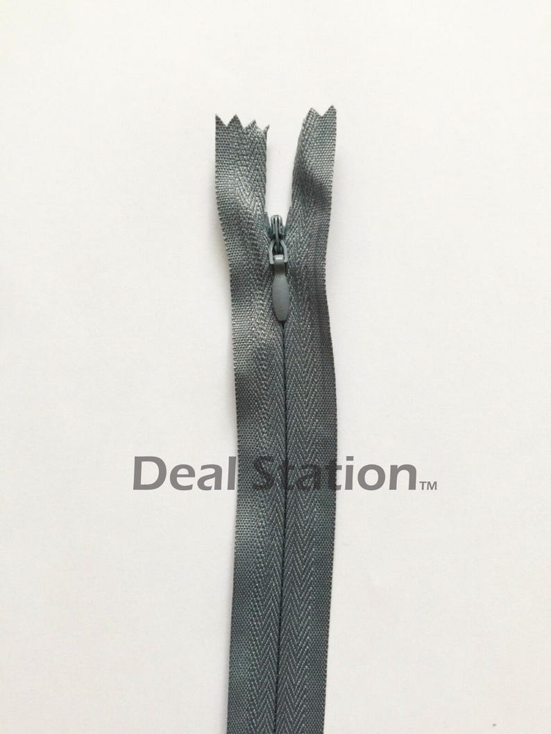 K&ouml;nnte beinhalten: Ein grauer, unsichtbarer Rei&szlig;verschluss mit passendem Zipper vor wei&szlig;em Hintergrund. Die Z&auml;hne des Rei&szlig;verschlusses sind im geschlossenen Zustand verdeckt. Der Text "Deal Station" ist im Hintergrund aufgedruckt.