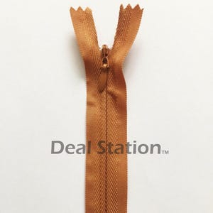 K&ouml;nnte beinhalten: Nahaufnahme eines braunen Rei&szlig;verschlusses mit passendem Zipper. Der Rei&szlig;verschluss ist ge&ouml;ffnet und zeigt die Z&auml;hne und das Stoffband. Der Text "Deal Station" ist auf dem Rei&szlig;verschlussband aufgedruckt.