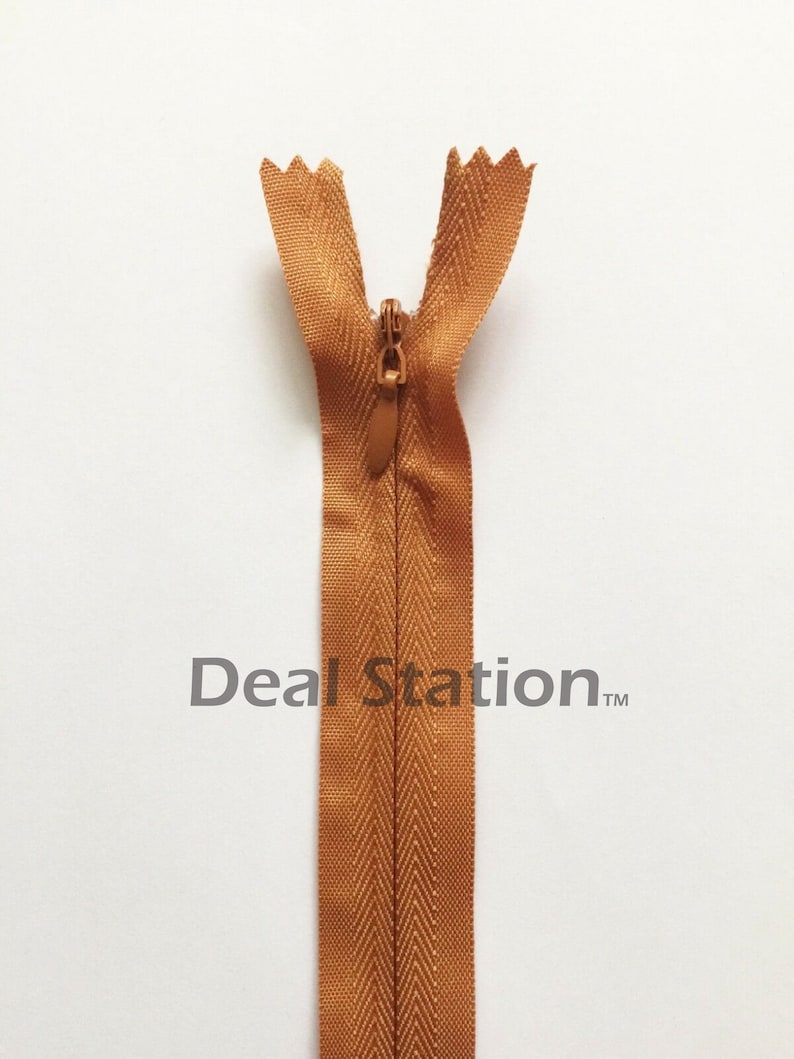 K&ouml;nnte beinhalten: Nahaufnahme eines braunen Rei&szlig;verschlusses mit passendem Zipper. Der Rei&szlig;verschluss ist ge&ouml;ffnet und zeigt die Z&auml;hne und das Stoffband. Der Text "Deal Station" ist auf dem Rei&szlig;verschlussband aufgedruckt.