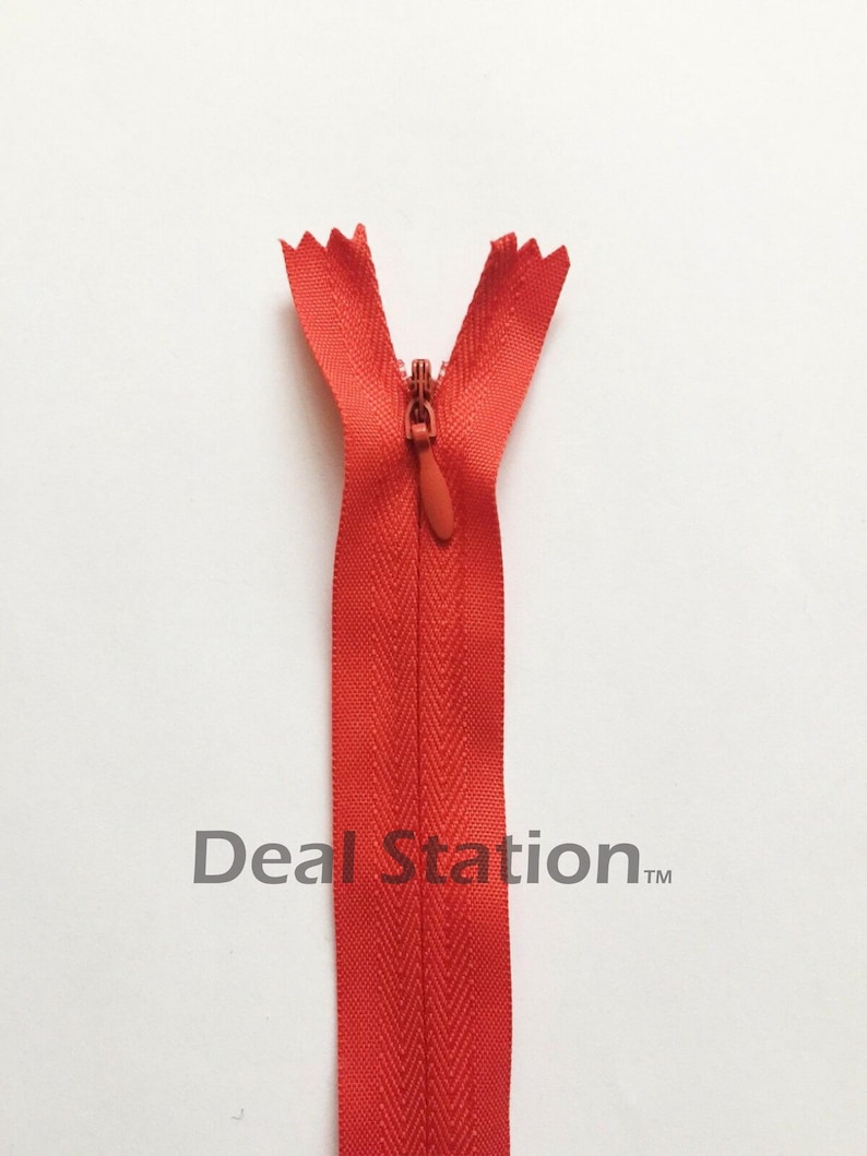 K&ouml;nnte beinhalten: Ein leuchtend roter Rei&szlig;verschluss vor wei&szlig;em Hintergrund. Der Rei&szlig;verschluss ist oben ge&ouml;ffnet und zeigt die Z&auml;hne und den Schieber. Der Text "Deal Station" ist grau am unteren Rand des Rei&szlig;verschlusses gedruckt.