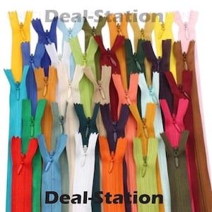K&ouml;nnte beinhalten: Eine Sammlung farbenfroher Rei&szlig;verschl&uuml;sse in verschiedenen Farbt&ouml;nen, darunter Rot, Blau, Gr&uuml;n und Gelb. Der Text "Deal-Station" ist in Wei&szlig; zu sehen. Diese Rei&szlig;verschl&uuml;sse sind wahrscheinlich f&uuml;r N&auml;h- oder Bastelprojekte gedacht.
