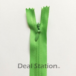 K&ouml;nnte beinhalten: Ein hellgr&uuml;ner Rei&szlig;verschluss mit passendem Schieber, offen und vor wei&szlig;em Hintergrund zentriert. Die Z&auml;hne des Rei&szlig;verschlusses sind oben sichtbar, und der Text "Deal Station" ist unten aufgedruckt.