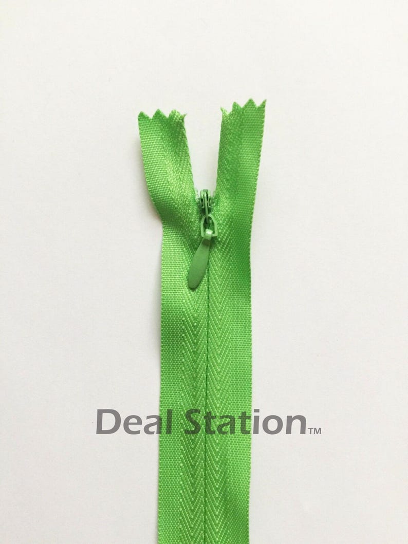 K&ouml;nnte beinhalten: Ein hellgr&uuml;ner Rei&szlig;verschluss mit passendem Schieber, offen und vor wei&szlig;em Hintergrund zentriert. Die Z&auml;hne des Rei&szlig;verschlusses sind oben sichtbar, und der Text "Deal Station" ist unten aufgedruckt.