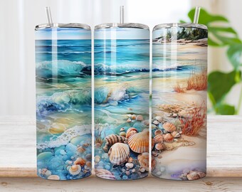 May include: Three stainless steel tumblers with a beach scene design. The tumblers feature a watercolor painting of ocean waves crashing on a sandy beach with seashells scattered on the shore.