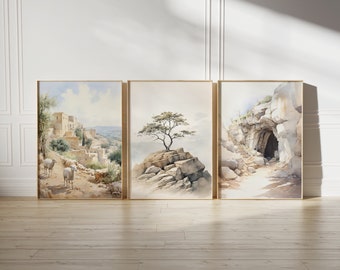 May include: Three framed watercolour paintings depicting different landscapes. The first painting shows a small village nestled in a hillside with sheep grazing in the foreground. The second painting features a lone tree growing on a rocky outcrop. The third painting shows a cave entrance in a rocky cliff.