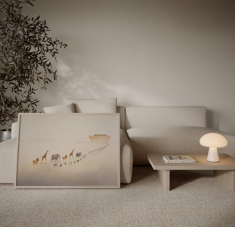 May include: A framed art print depicting a line of animals, including giraffes and elephants, walking towards a boat. The artwork is in soft, neutral tones and is displayed on a beige sofa. A small, white mushroom-shaped lamp sits on a wooden side table.