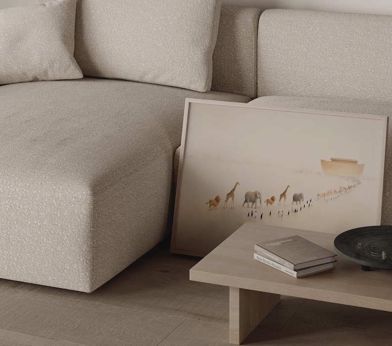 May include: A framed art print depicting a procession of animals, including lions, giraffes, and elephants, walking towards an ark. The artwork is set against a muted, beige background. A light wood coffee table holds books and a decorative bowl.