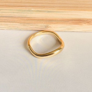 May include: A gold-coloured ring with a square shape. The ring is made of a smooth, shiny metal.