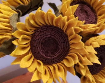 Könnte beinhalten: Ein Strauß aus Filz-Sonnenblumen mit braunen Zentren und gelben Blütenblättern. Die Sonnenblumen sind in einer Vase angeordnet.
