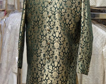 Puede incluir: Chaqueta de brocado verde y dorado con cuello mandarín y cierre de botones. La chaqueta presenta un estampado floral completo y se exhibe en un maniquí. La prenda forma parte de una colección de ropa formal.