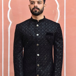 May include: A black long-sleeved kurta with a high collar and button closure. The kurta is adorned with a geometric pattern of sequins and has a pocket on the left side.