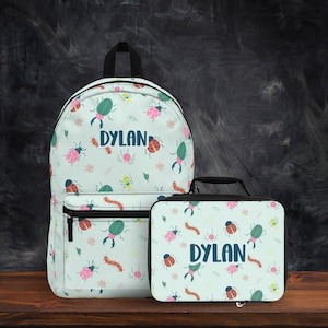May include: A blue and white backpack and lunch bag set with a bug pattern and the name "Dylan" printed on both.
