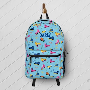 May include: A light blue backpack with a colorful pattern of roller skates and the name "Carly" printed on the front.