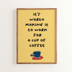 Peut inclure: Une affiche encadrée avec un fond jaune et le texte "It's worth making it to work for a cup of coffee." Une tasse à café bleue avec une soucoupe rouge est en bas. Le cadre est marron.