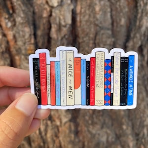May include: A sticker of a bookshelf with the spines of 14 different books. The books are all different colors and have different titles. The titles include "The Kill Runner", "Forever", "To Kill a Mockingbird", "Bridge to Terabithia", "Mice Men", "The Giver", "The Bluest Eye", "The Handmaid's Tale", "Margaret Atwood", "The Color Purple", "A Wrinkle in Time", "Absolutely True Diary of a Part-Time Indian", and "Walker".