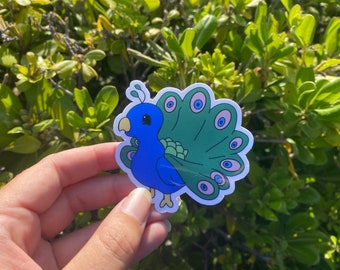 May include: A blue and green peacock sticker with a cartoon-like design. The peacock has a large, colourful tail with a pattern of eyes.