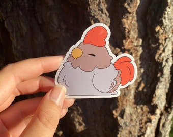 May include: A sticker of a cartoon chicken with a red comb, brown body, and white feathers. The chicken has a yellow beak and closed eyes.