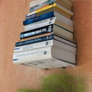Op de afbeelding: Een stapel boeken op een plank, met titels zoals "Trading-Psychologie", "Das Spiel der Spiel", "Think and Grow Rich" en "Generations of Capital".