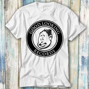 Peut inclure: T-shirt blanc avec un logo noir et blanc qui dit "Good Looking Records" avec un visage de dessin animé d'un homme au centre.