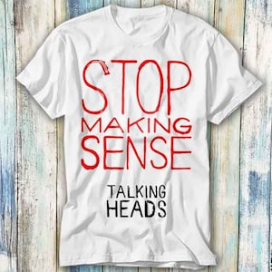 May include: White t-shirt with red text that says "Stop Making Sense" and "Talking Heads" in black text.