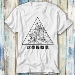 Könnte beinhalten: Weißes T-Shirt mit einer Schwarzweißillustration eines Charakters aus dem Anime "Ghost in the Shell". Der Charakter sitzt in einem Dreieck mit dem japanischen Text "攻殻機動隊" darunter.