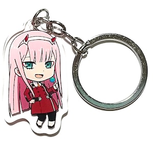 May include: A pink-haired anime character with blue eyes and a red jacket is featured on a keychain. The character is holding a blue lollipop. The keychain is made of clear acrylic and has a silver metal ring.
