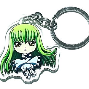 Op de afbeelding: Een sleutelhanger met een anime-personage met groen haar en een witte jurk.
