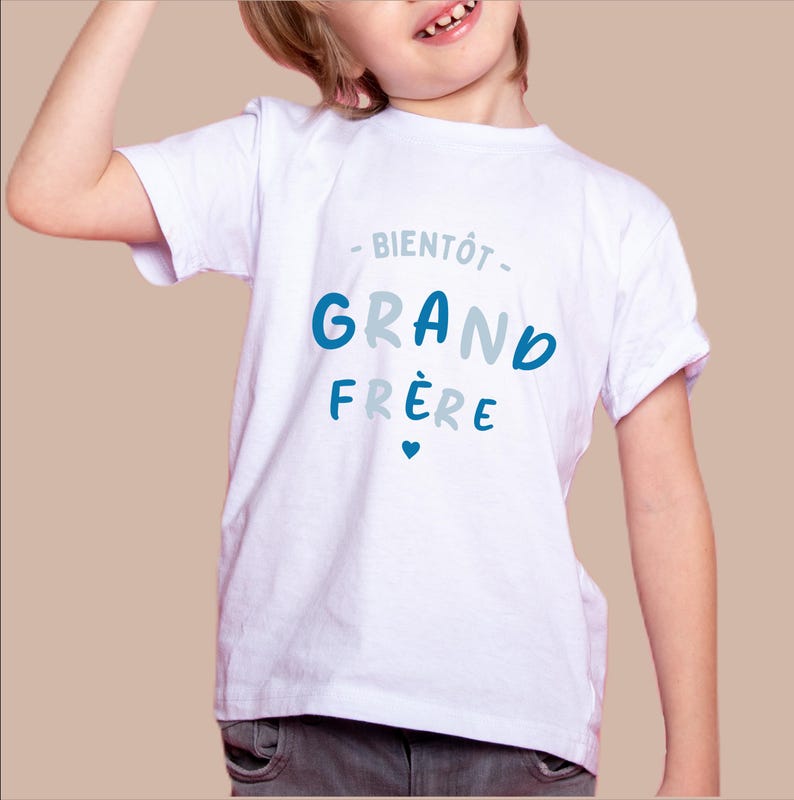 K&ouml;nnte beinhalten: Wei&szlig;es T-Shirt mit blauem und grauem Text, der "Bient&ocirc;t Grand Fr&egrave;re" mit einem kleinen Herzen sagt.