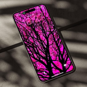May include: A smartphone with a vibrant magenta and black tree silhouette wallpaper. The screen displays the time 18:27, the date Sa. 3. Okt., and icons for a flashlight and camera. The device features a thin metallic frame and a notch at the top.