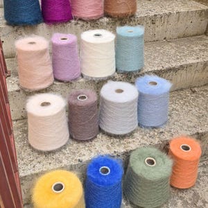 以下が含まれることがあります： 青、紫、ピンク、茶色など、さまざまな色合いのカラフルな糸巻きのコレクション。 糸はふわふわで柔らかく、編み物や編み物プロジェクトに最適です。 糸巻きはコンクリートの階段に配置されています。