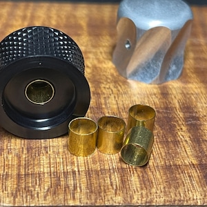 May include: A black knob with a diamond pattern and a brass insert. Four brass rings are also shown.