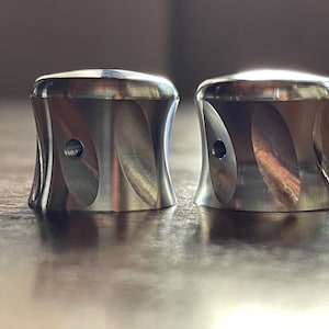 Peut inclure: Deux boutons en métal argenté avec un motif en spirale. Les boutons ont un petit trou au centre.