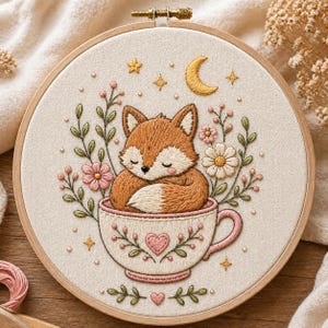 Peut inclure: Broderie sur tambour représentant un renard endormi dans une tasse à thé. Le renard est orange et blanc, entouré de fleurs, d'étoiles et d'un croissant de lune. La tasse est blanche avec des accents roses et un cœur.
