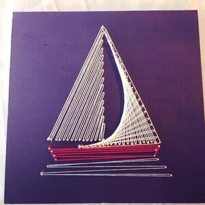 May include: A white sailboat with a red hull is created using string art on a purple background.