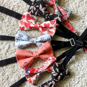 Peut inclure: Une collection de nœuds papillon avec différents motifs, notamment des cœurs, des cerises et des motifs floraux. Les nœuds papillon sont noirs, rouges, roses, bleus et blancs.