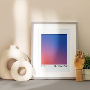May include: A framed print with a gradient of blue, purple, and red colors. The print has the text "222 ALIGNMENT" at the bottom. The print is on a table with two white ceramic vases and a wooden hand figurine.