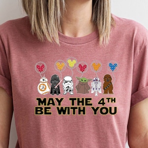 May include: A pink t-shirt with a graphic of Star Wars characters holding balloons that say "May the 4th Be With You".